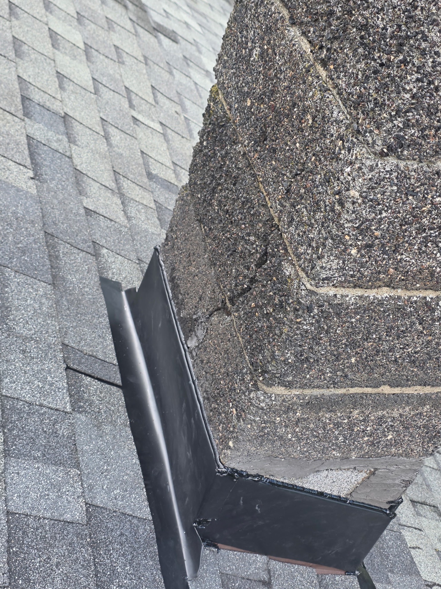 New black chimney flashing installed with asphalt shingles on a Batavia roof