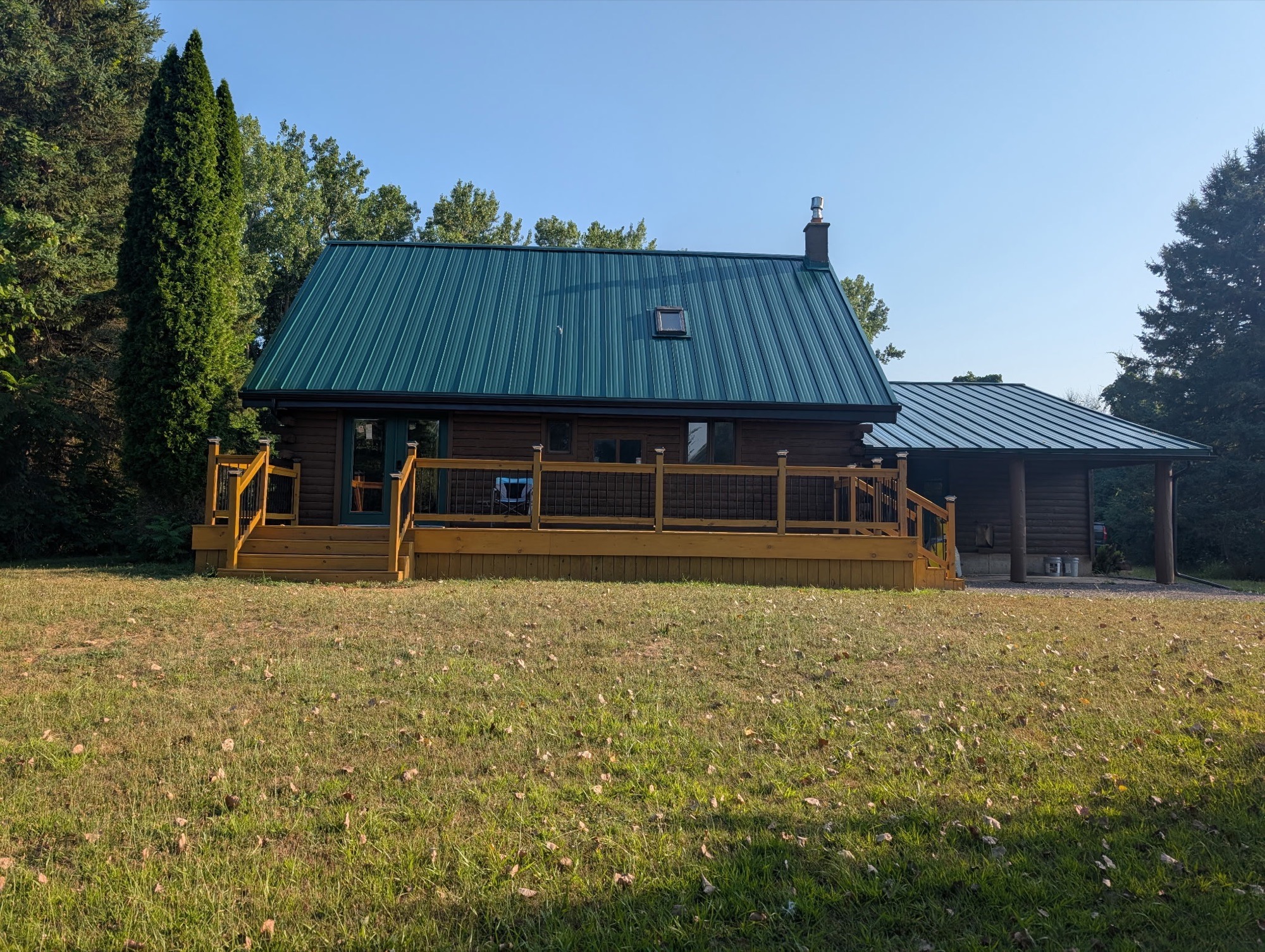 Rear of Pembroke home after green metal roof installation and deck work